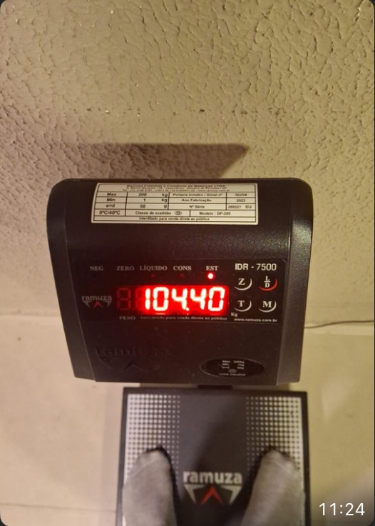 Foto real da balança marcando 104,40kg, feedback de aluno do Brick by Brick
